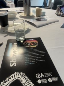 An a4 piece of paper showing the schedule for the program, resting on a table with a water glass.