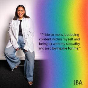 A woman dressed in jeans and white shirt against a rainbow background.